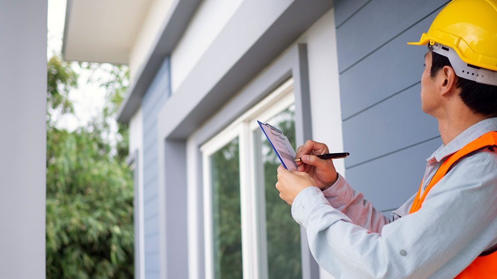 Home inspector with clipboard inspecting home exterior