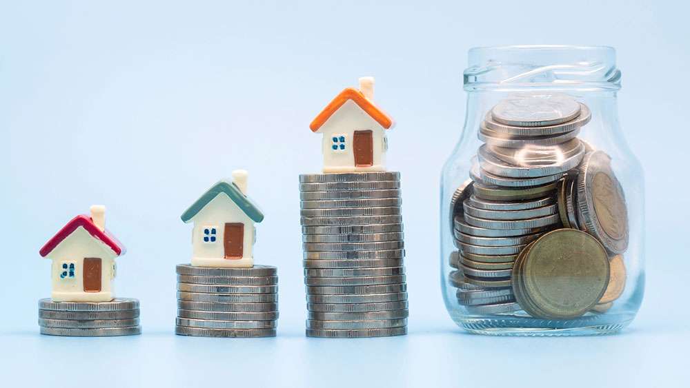 Miniature houses on increasingly taller stacks of coins.