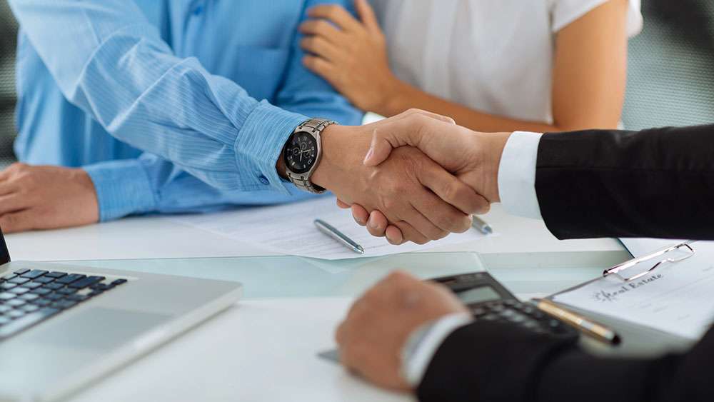 Real estate agent shaking hands with new clients